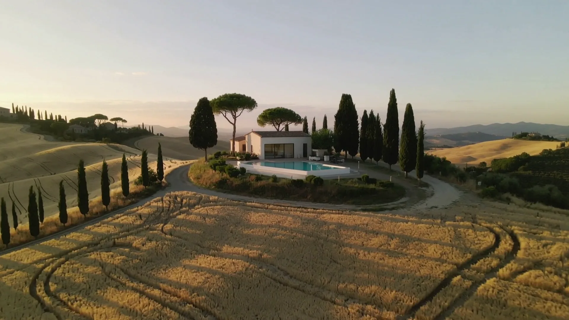 Flight over Tuscan hills toward a modern agriturismo at golden hour